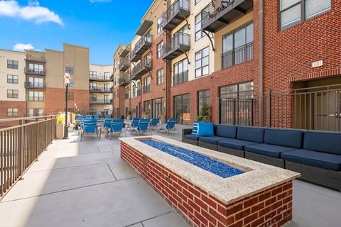 A brick wall with a blue water feature in front of apartment buildings.